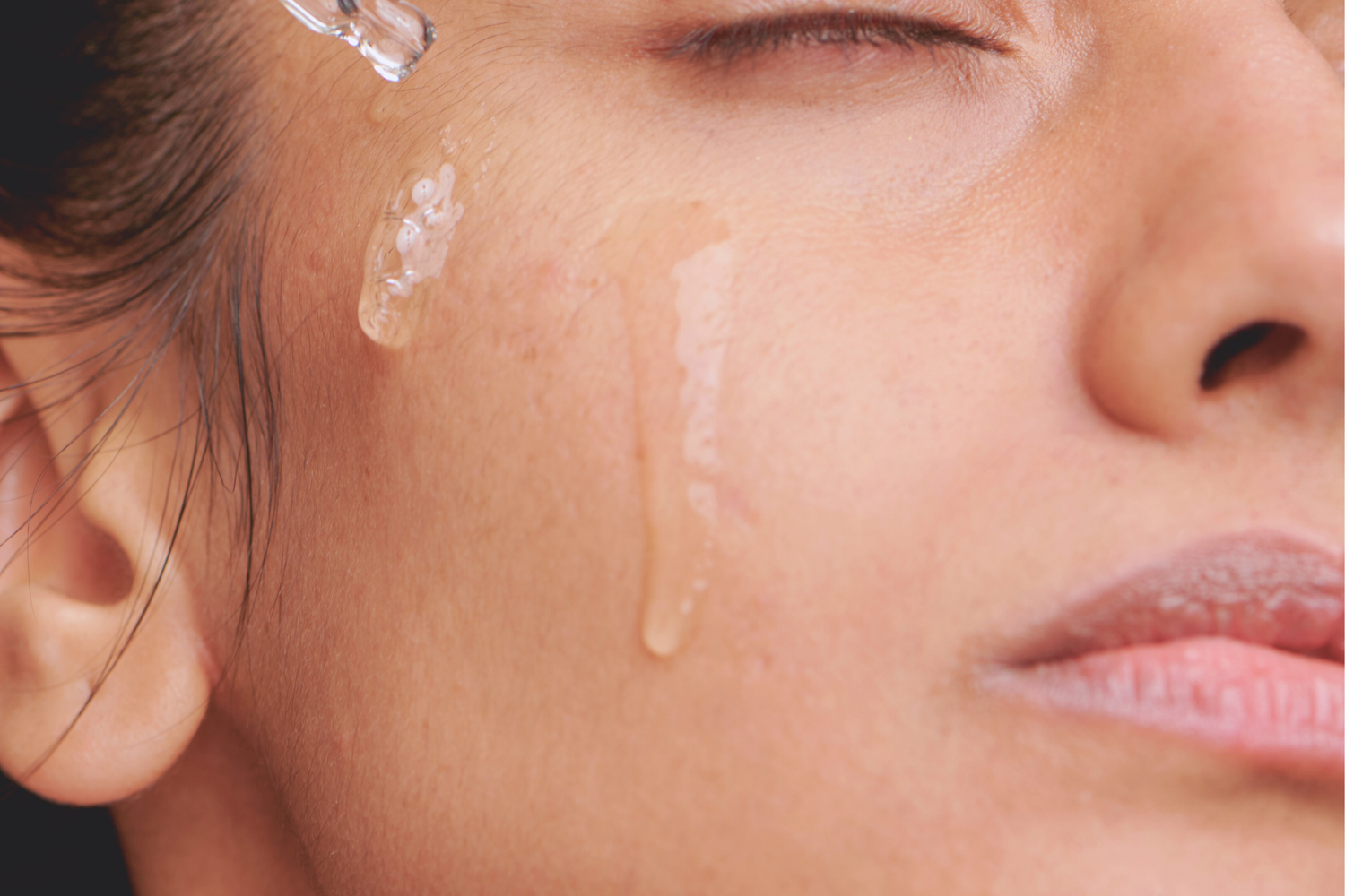 Femme à la peau mate applique sur son visage le sérum Élixir D'amour de Mawu Paris avec la pipette.