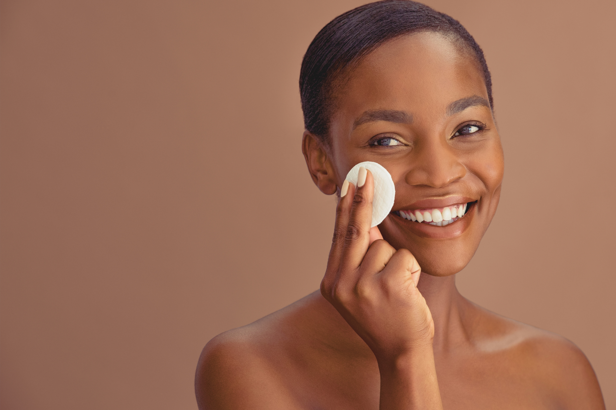 Une jolie femme noire, cheveux lisses, passe un disque de coton sur sa joue droite.