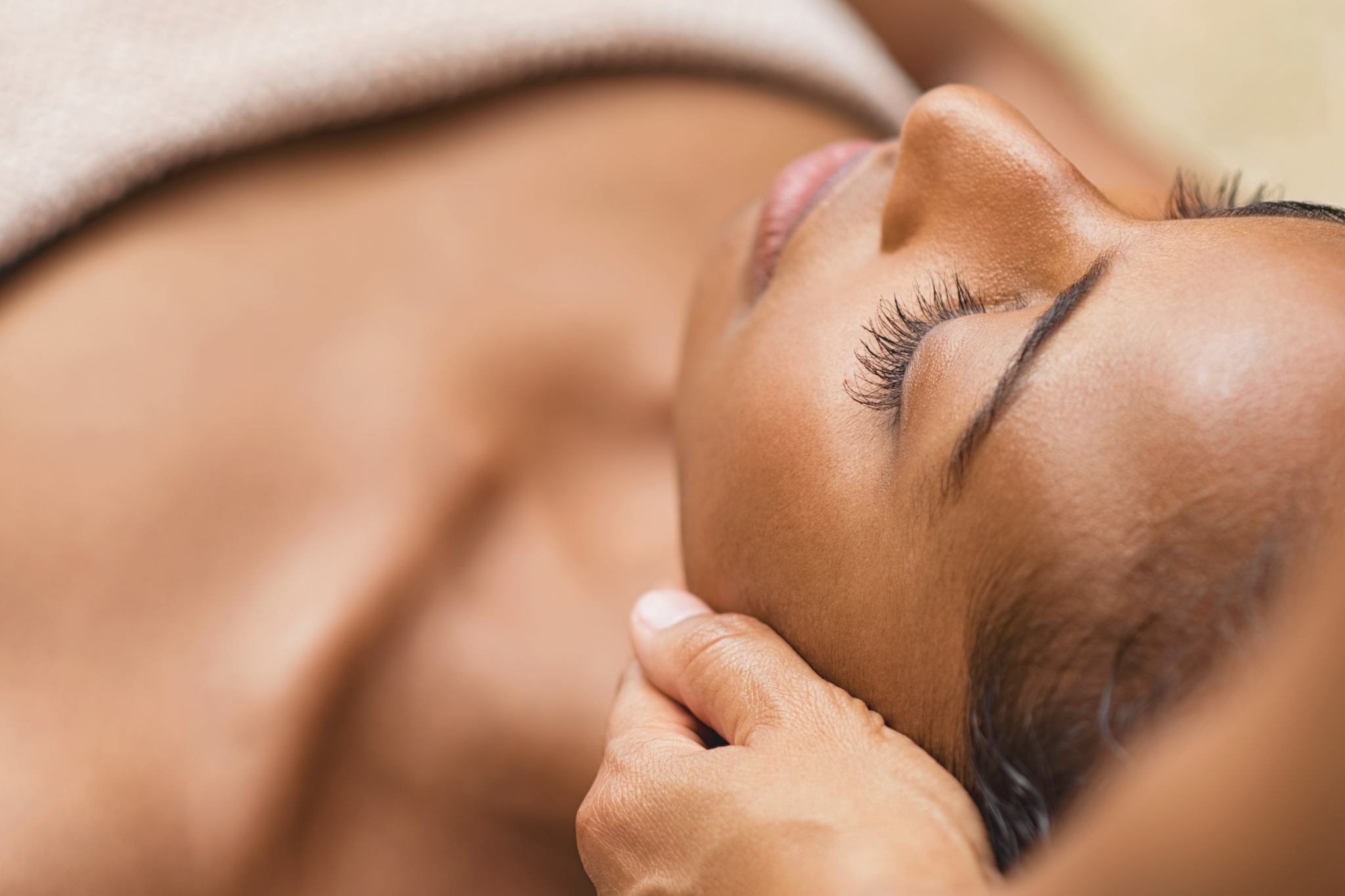 Femme noire à la peau marron allonger sur le dos. Massage du visage.