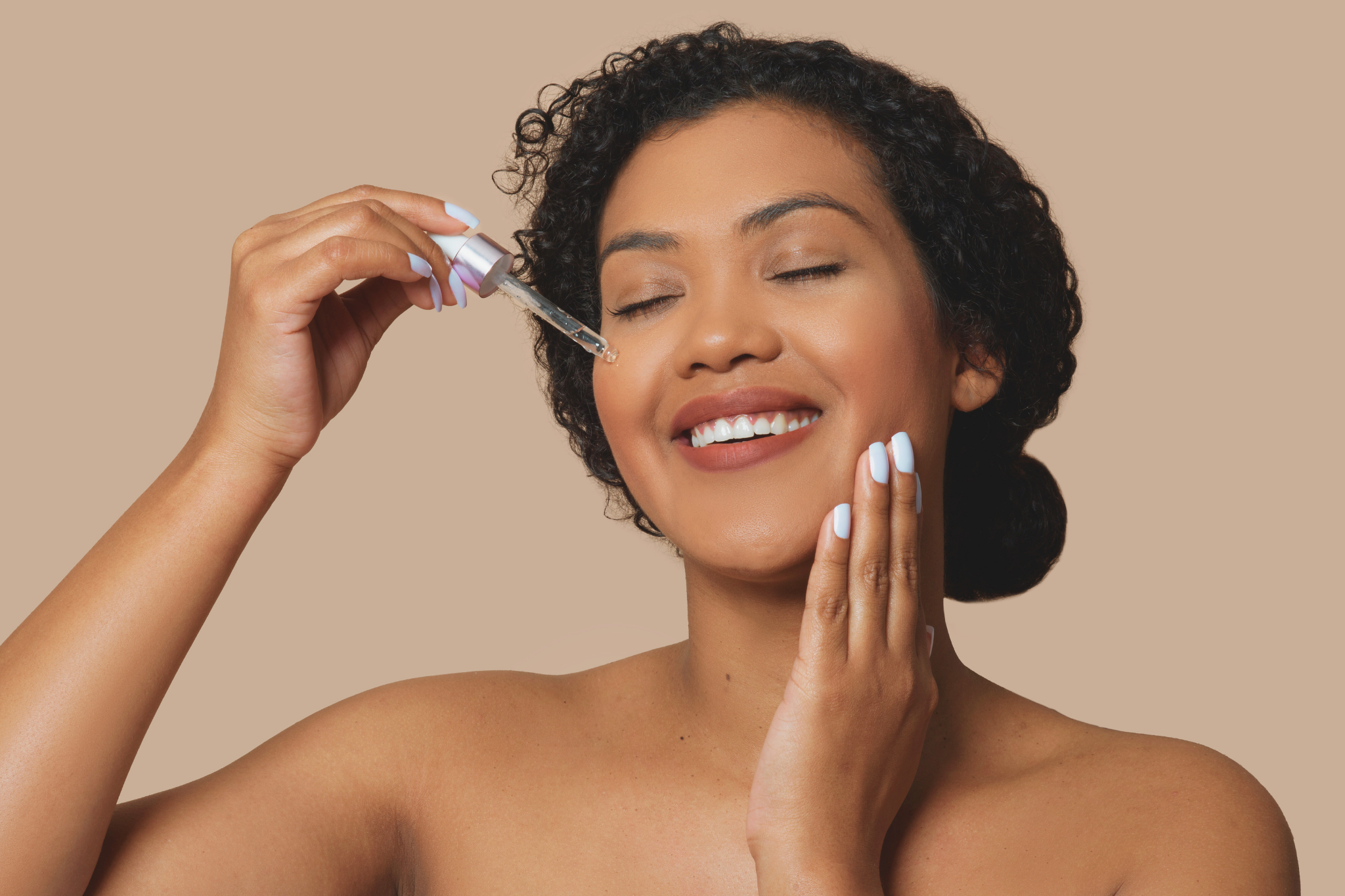 Une belle femme métisse à la peau mate, avec une belle manucure, applique le sérum nourrissant Élixir D'amour de Mawu Paris.