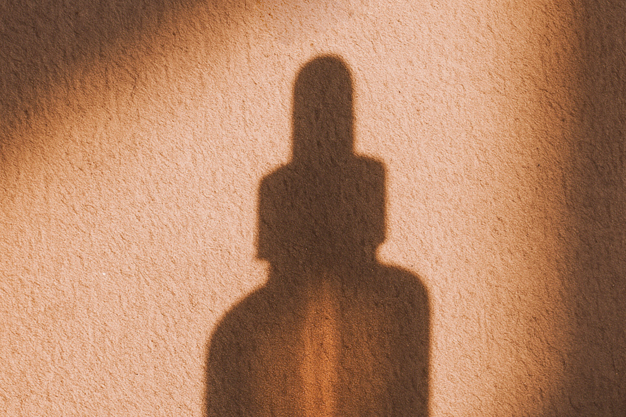 Ombre du sérum visage nourrissant Élixir D'amour de Mawu Paris, sur un mur couleur sable.