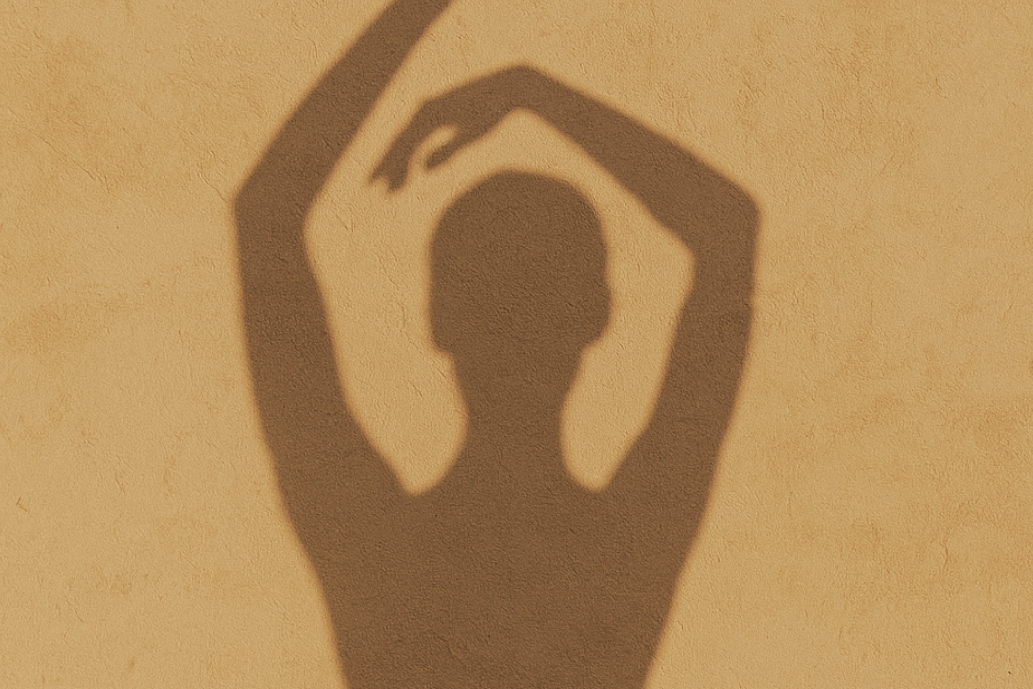 L'ombre d'une femme sur un mur couleur sable.
